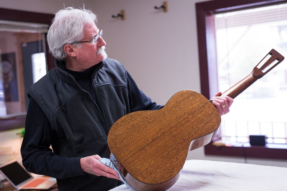 Preston Thompson looking at a parlor acoustic guitar